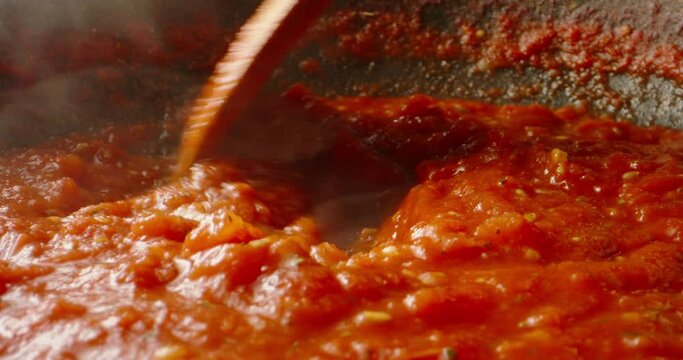Tomato sauce boiling in a pan, being stirred with a spoon. Hot tomato sauce cooked for pizza or pasta. Italian cuisine, food and drink 4k footage