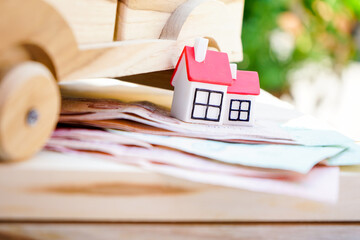 Miniature house and wooden car with money for life planning, real estate, housing property, buying and selling home