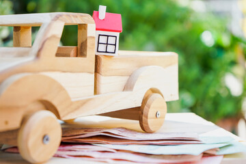 Miniature house on wooden car with money for life planning, real estate, housing property, buying and moving home