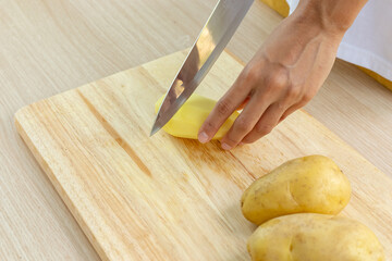 chef slicing fresh potatoes on cutting board