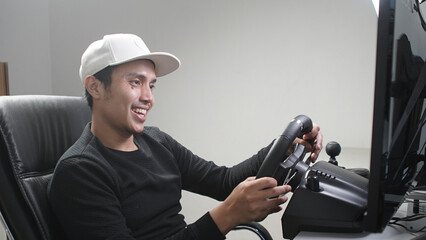 smiling Casual Asian young man playing racing game simulation
