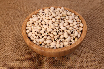 Blackeye beans in wooden bowl on jute yarn fabric background