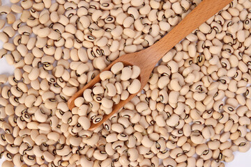 Blackeye beans in wooden scoop spoon top view on white background