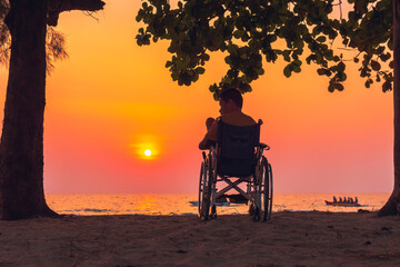 Obraz premium Asian special child on wheelchair on the sea beach with sunset on travel time in holiday family and learning about nature around the sea,Lifestyle in the education age kids,Happy disabled kid concept.