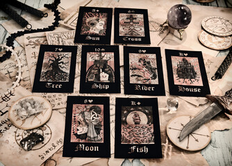 Lay out of tarot cards with old parchments and paper with magic spells on witch table.