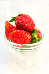 big ripe strawberries in a glass cup on a white background