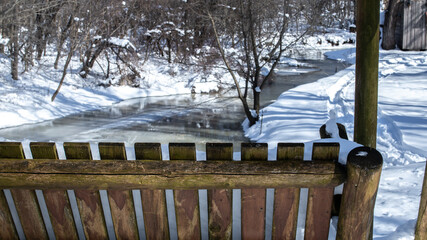 Cedar log rocking chair - designed for the outdoors - swings back and forth on a winter February morning in Southwestern Ontario, Canada, overlooking a melting creek. 