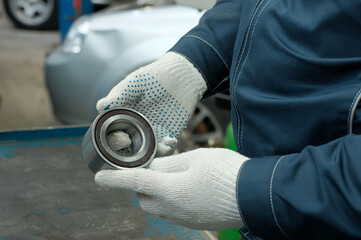 A mechanic inspects a new hub bearing before replacing it during car repairs and maintenance at a...