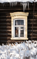 Winter window with icicles on a wood house.