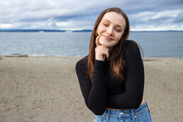 Teenage girl outside at Alki Beach in West Seattle with a view of the Puget Sound and the city of...