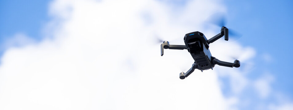 February 7, 2021, Everett, Washington: Mavic Mini II drone in flight under blue sky with puffy white clouds