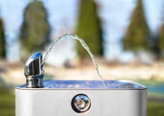 Drinking water fountain in park on a sunny day, no person. Close up of flowing water from the tab...