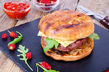 Homemade burger with sesame bun and ground beef on black stone. Studio Photo