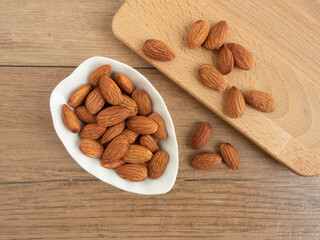 Organic almonds nuts in ceramic bowl with wooden butcher on wooden table. Set or collection for healthy nuts and vegetarian food concept.