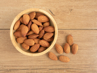 Organic almonds nuts in wooden bowl on wooden table. Top view. Flat lay. Set or collection for healthy nuts and vegetarian food concept.