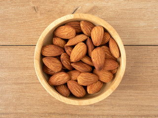 Organic almonds nuts in wooden bowl on wooden table. Top view. Flat lay. Set or collection for healthy nuts and vegetarian food concept.