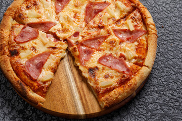 Pepperoni pizza, on a black textured background. Italian food concept. Close-up.