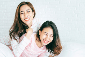 Two pretty best friends forever girlfriend talk, hug and laugh together on bed at cozy home relation fall in love. Lesbian couple homosexual happy lifestyle on bed. LGBTQ relation lifestyle concept.