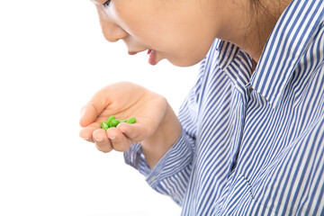 The female patient in front of the white background is eating the medicine in her hand