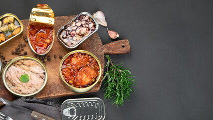 Various canned fish and seafood in aluminum cans. On dark gray background.