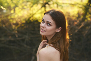 Naklejka premium happy red-haired woman on nature in the forest near green trees Summer sun