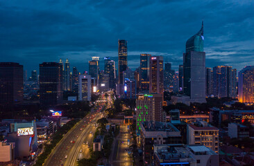 Night aerial wide view of skyscrapers and multi lane highway in large urban city center Cityscape of high rise buildings in Jakarta, Indonesia at night