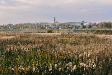 autumn evening landscape with a field and a river and a Christian Church on the horizon