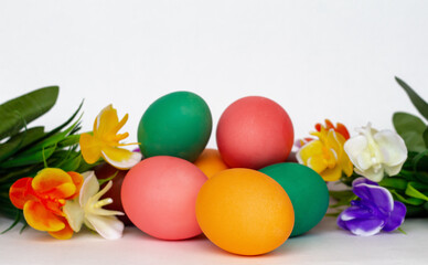 Fototapeta na wymiar a heap of bright multicolored Easter eggs among flowers isolated on white background, copy space