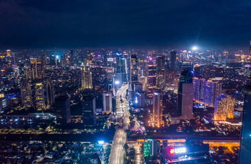 Fototapeta na wymiar Aerial night cityscape of skyscrapers and multi lane highway traffic in modern city center of Jakarta, Indonesia Urban city center with high rise buildings at night