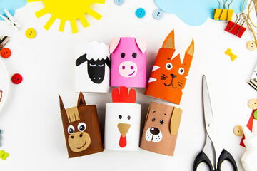 Children's crafts farm pets from toilet sleeves. View from above on diy of farm animals: horse, sheep, scrolls, rooster, dog, cat. Instruction step by step with the child's paper.