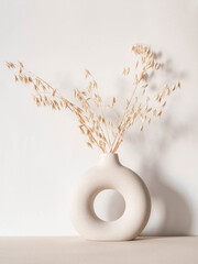 Round stylish ceramic vase with dried oats