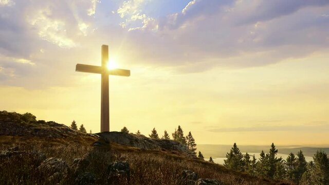 A cross with the setting or rising sun in background, religious belief concept