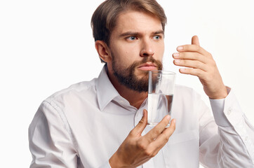 A gentleman in a white shirt holds a glass of water in his hand on a light background