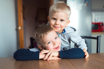 Happy little boys brothers hug at kitchen