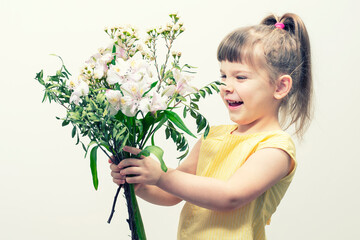 cute kid girl in a yellow blouse with a bouquet of white flowers. colors of the year. March 8...