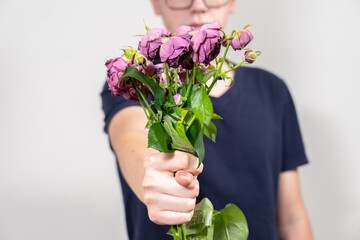 man is holding a bouquet of dead and withered flowers and shows FIG