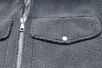 Detail of the zipper and pocket of a black wool jacket.