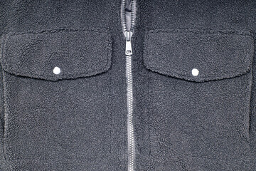 Detail of the zipper and pocket of a black wool jacket.