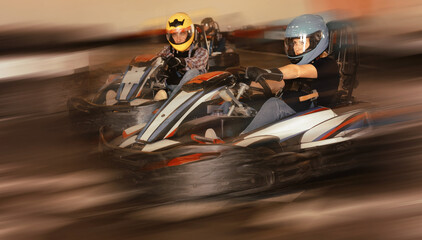 Group of positive smiling people driving go-carts at racing track © JackF