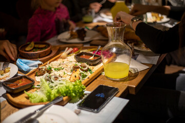 festive table with wine and mixed meat with salad and sauce on a chalkboard with lemonade for company, horizontal