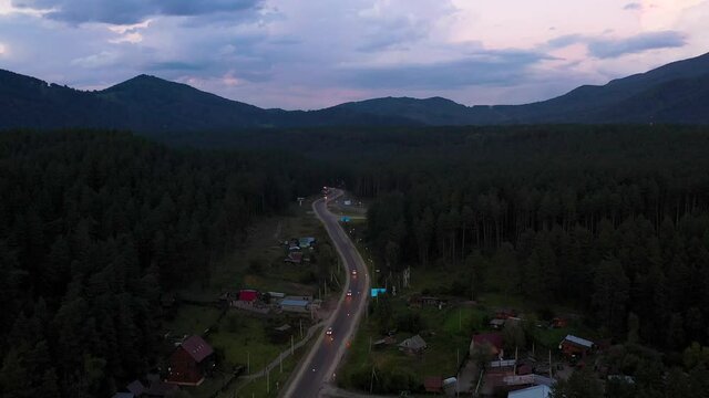 Night road along the forest, shooting from a height. Twilight
