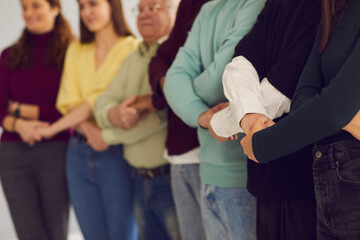 Midsection shot of group of diverse people standing together and holding hands, supporting each...