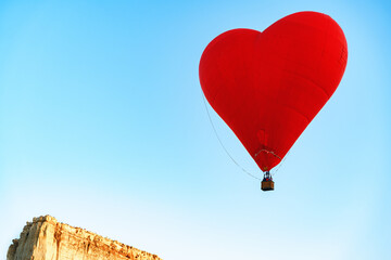 Fototapeta na wymiar Red heart-shaped air balloon flying in the sky