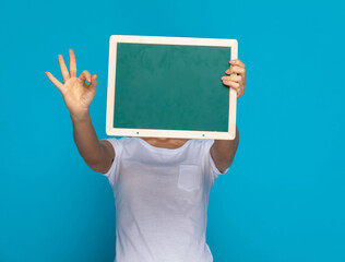 casual woman hiding behind a green board