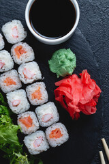 Sushi rolls with salmon, rice, eel and soy sauce on dark stone background