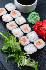 Sushi rolls with salmon, rice, eel and soy sauce on dark stone background