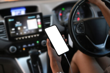 Young woman using smart phone while driving behind the wheel.