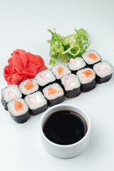 Sushi rolls with salmon, rice and soy sauce on a light background