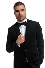 sexy bearded man in black tuxedo holding hand in pocket