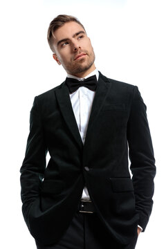 handsome unshaved man in black tuxedo holding hands in pockets